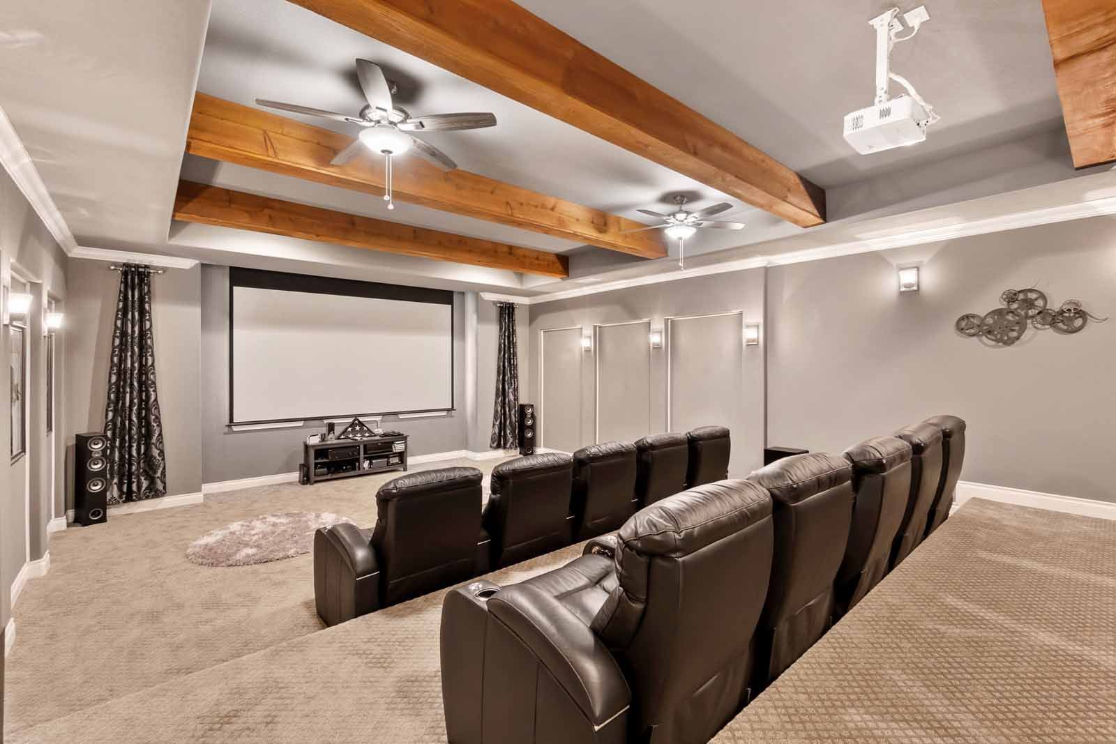 A home theater with a projector screen and a ceiling fan.