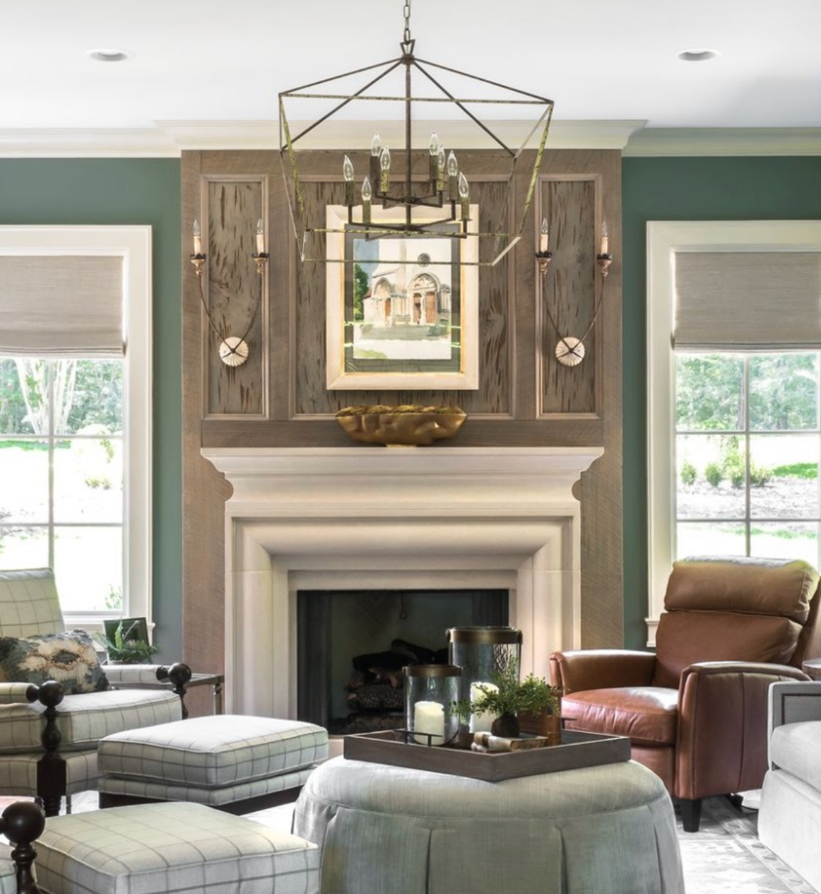 Living room with fireplace, wood paneling, green walls, light fixtures, chairs, and window views.