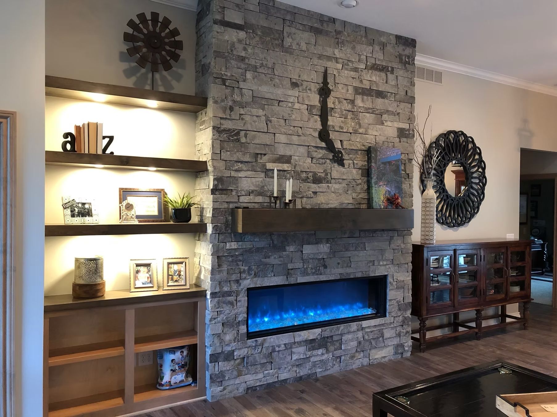Stone fireplace with blue fire effect, built-in shelves, and dark wood mantel.