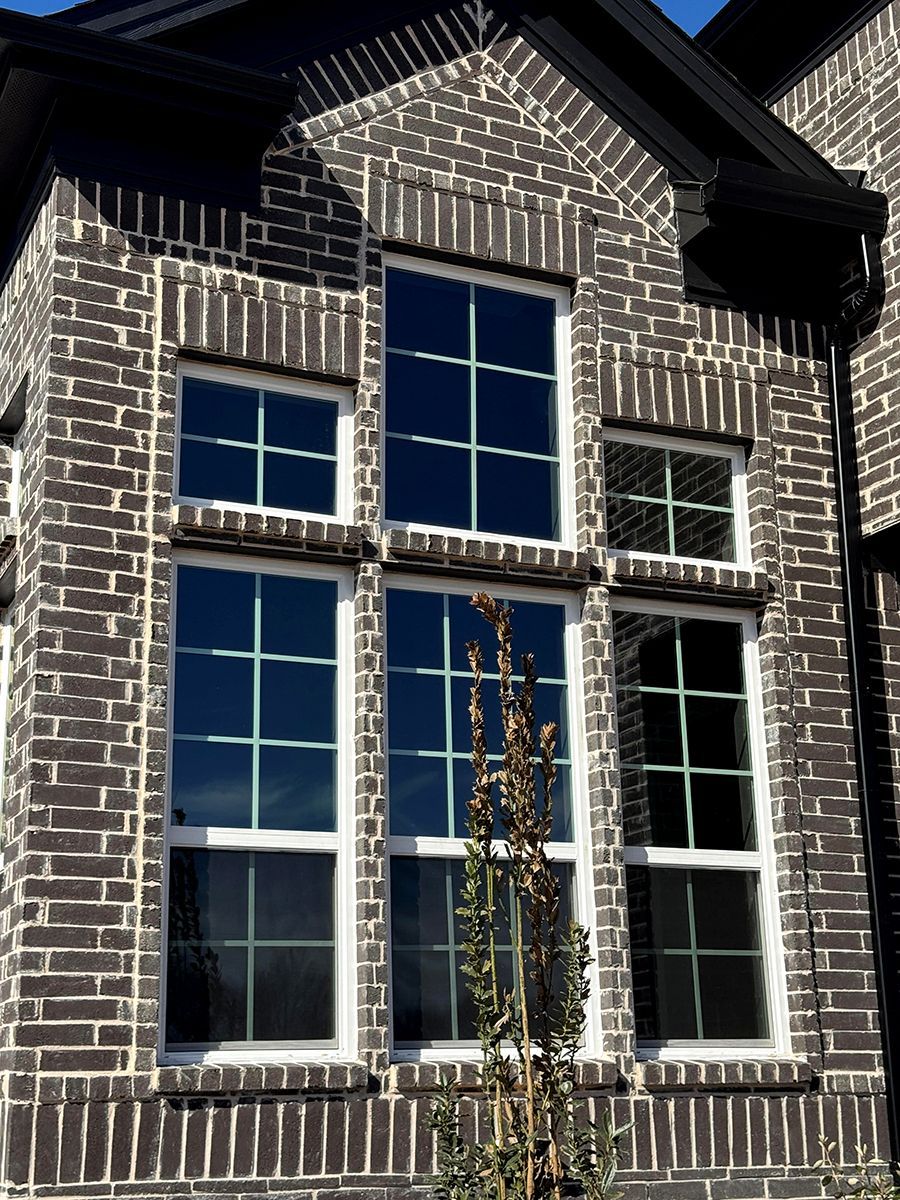 Brick facade with six white-framed windows of varying sizes, the tallest ones below.