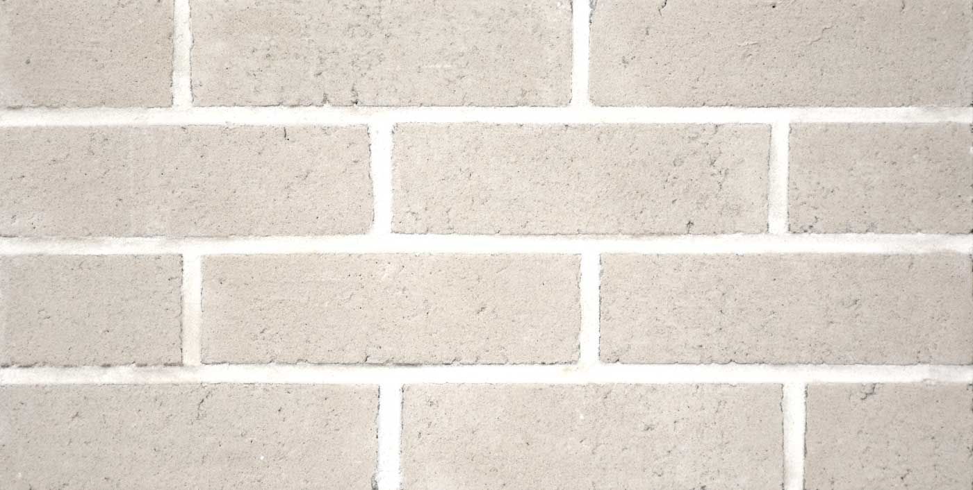 Close-up of a brick wall with light gray bricks and white mortar.