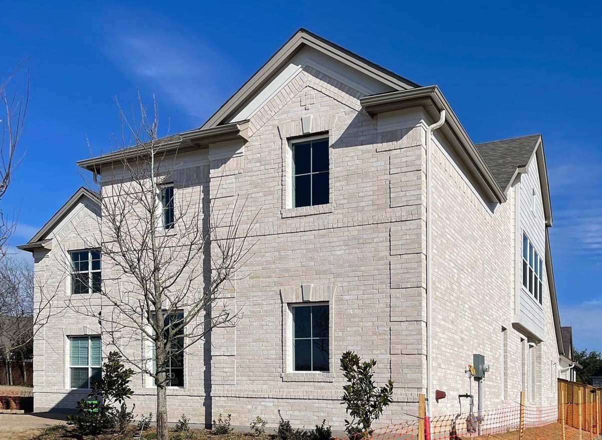 Two-story brick house with multiple windows against a clear blue sky.