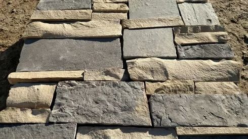 Close-up of a stone wall in shades of gray and tan. The stones are rectangular and stacked.