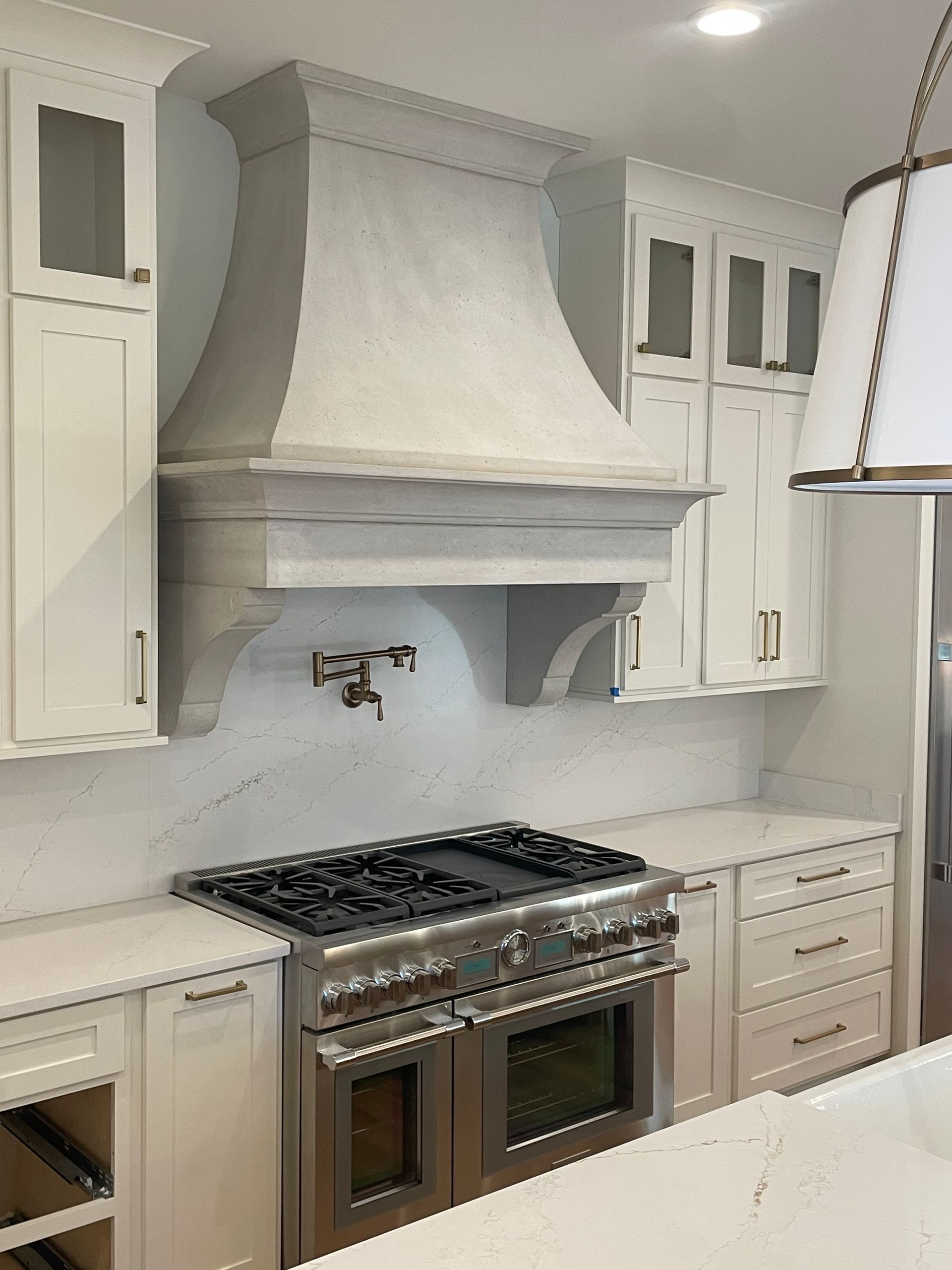 White kitchen with range, hood, and cabinetry.