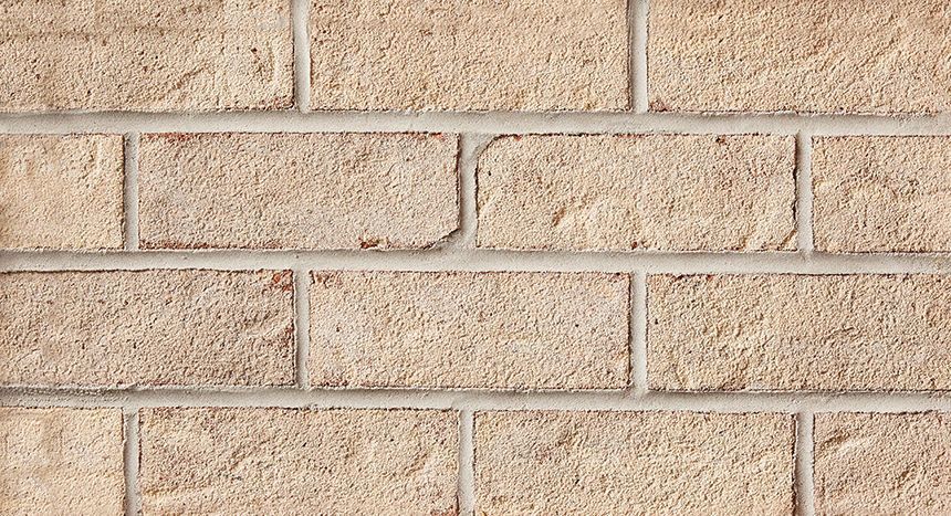 Tan brick wall with gray mortar.