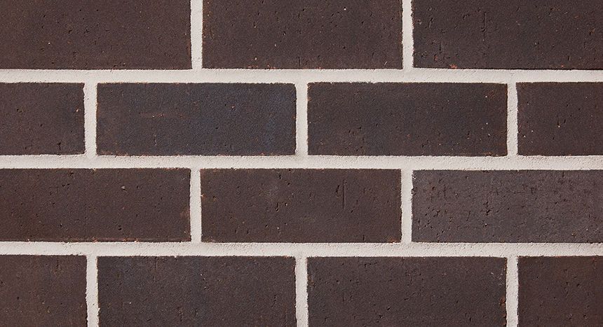 Dark brown brick wall with white mortar.