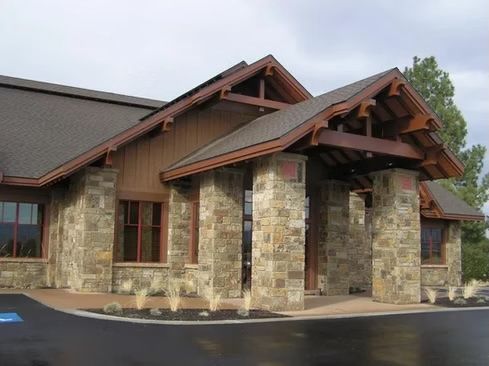 Building exterior with stone columns and brown roof, entry way.