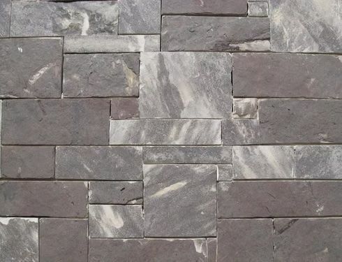 Close-up of a wall with dark gray and white rectangular stone tiles in a stacked pattern.