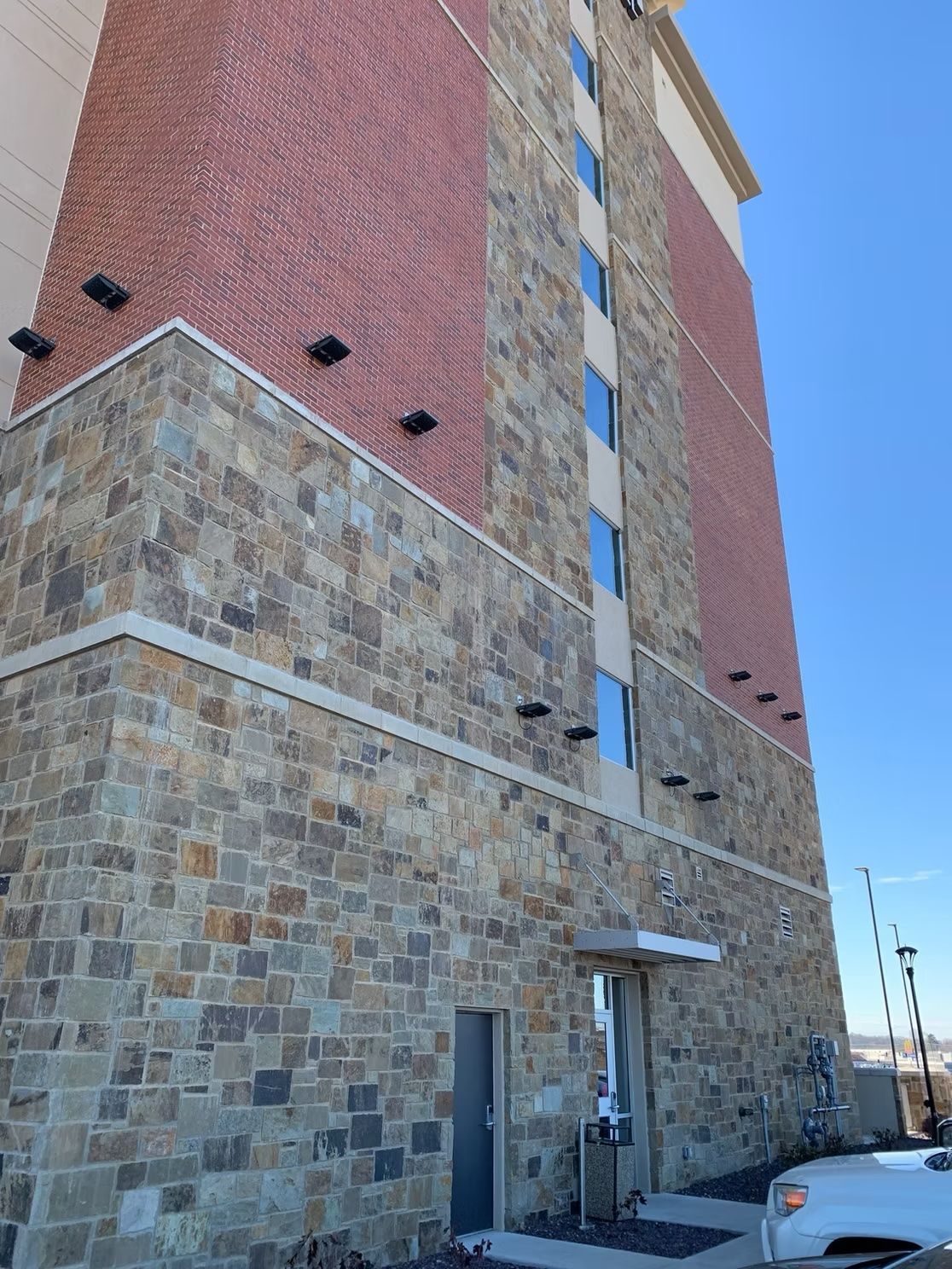 Multi-story building with stone and brick exterior against a blue sky.