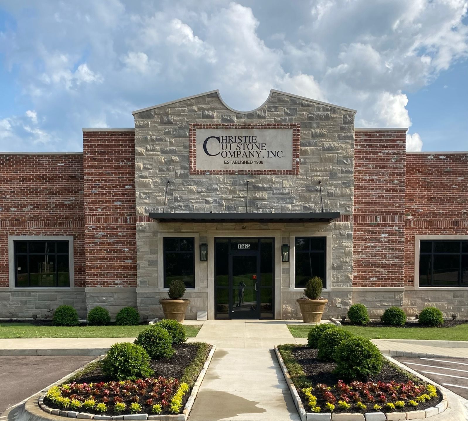 Exterior of Christie Design Company Inc. building with stone and brick facade, landscaping.