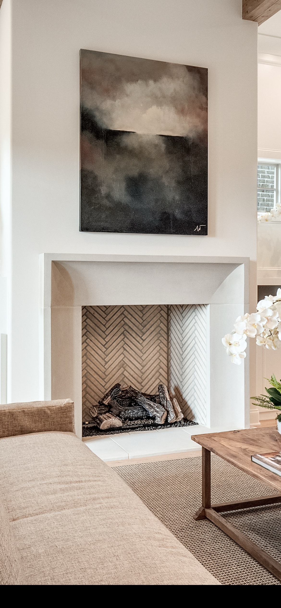 Fireplace with artwork and rug in a room. Neutral colors, modern design.