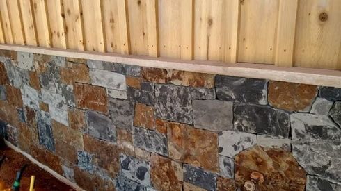 Stone wall cladding with wood paneling above. Brown, gray and tan stone.
