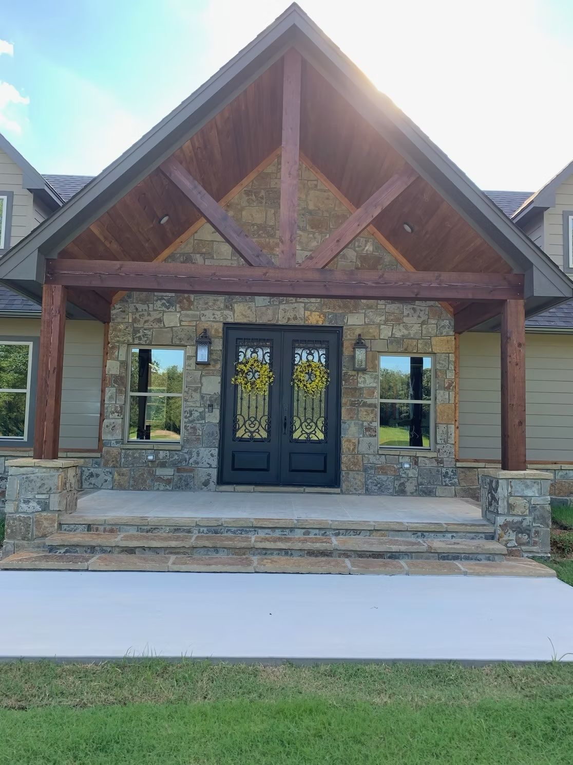 Stone-faced entryway with wooden beams, black double doors