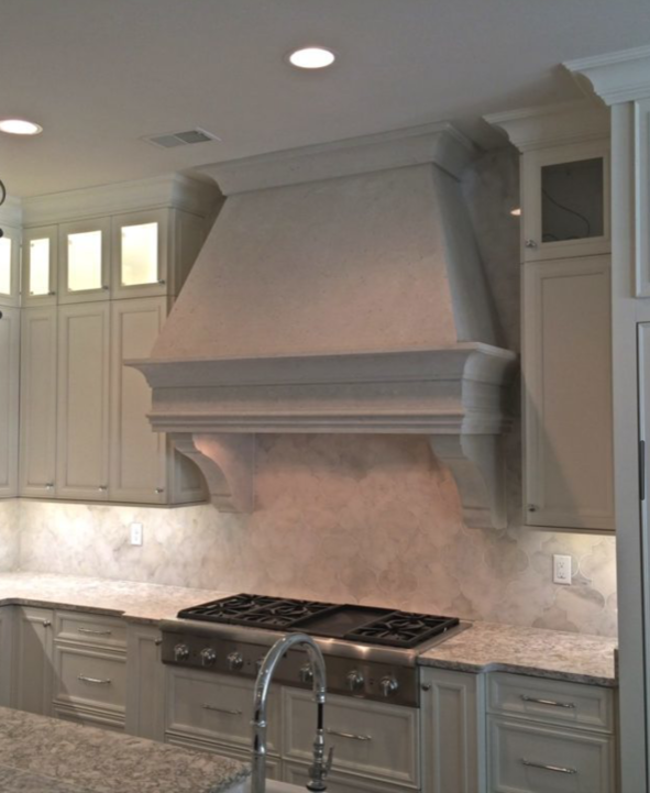 Kitchen with light gray cabinetry and a large, ornate range hood above a stovetop.