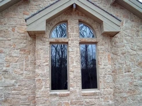 Facade of a building with arched and rectangular windows set in light brown stone.