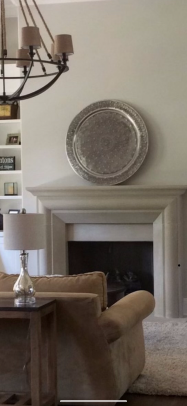 A living room with a fireplace, sofa, and a decorative plate above the mantel.