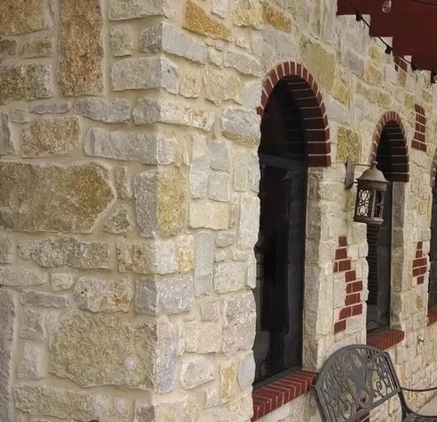 Stone building exterior with arched openings, red brick trim, and a decorative outdoor light.
