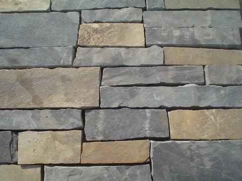 Close-up of a wall made of rectangular, rough-hewn stones in shades of gray and tan.