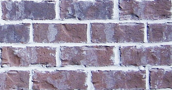 Brick wall, primarily brown bricks with white mortar.