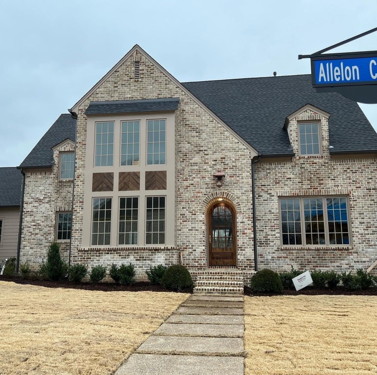Brick house with a dark roof and a walkway, street sign 
