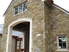 Stone exterior of a building with an arched entrance and windows.