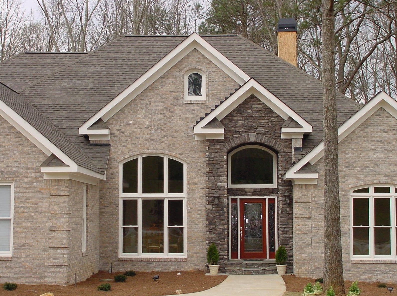 Beige brick house with arched windows and stone accent around the entrance.
