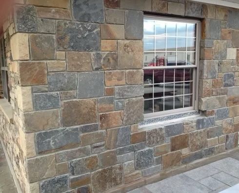 Stone exterior wall with window, showcasing various earthy tones and textures.