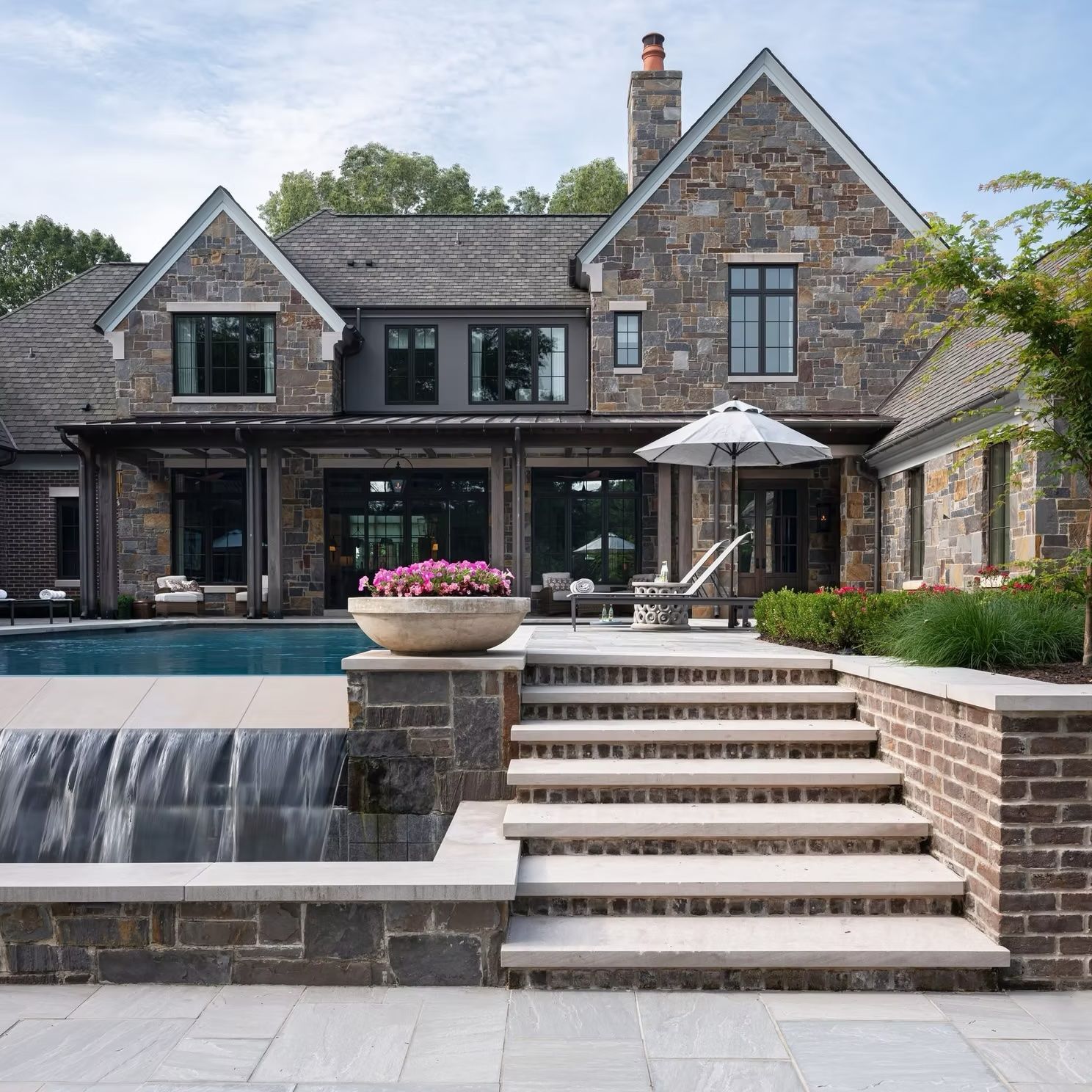 Stone house with pool and steps; waterfall feature and outdoor seating area.