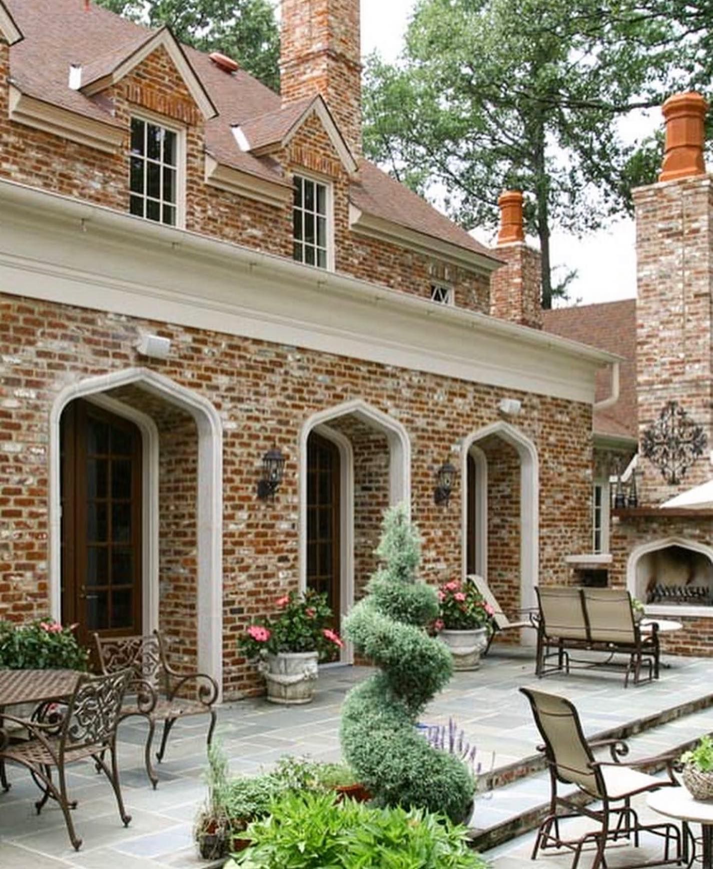 Brick house with arched doorways, outdoor patio, and fireplace.