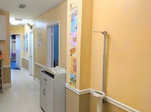 Hallway in a pediatrician's office, with weight scale and growth chart. Light yellow walls, white trim.