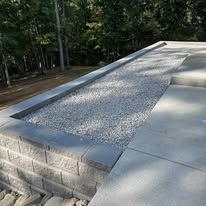 Outdoor concrete bench with a gravel-filled top beside a wooded area