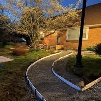 Curved concrete walkway beside a brick building, with white edging and a black lamppost.
