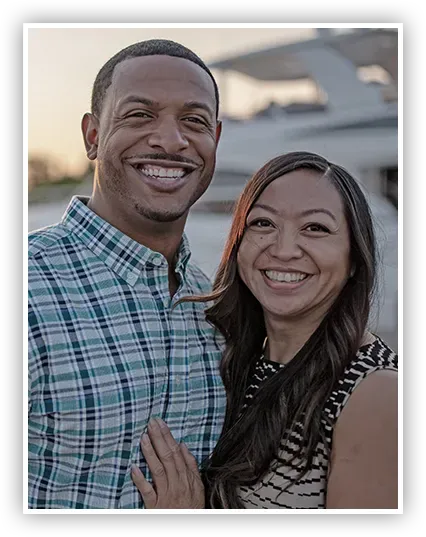 A man and a woman are posing for a picture and smiling for the camera.