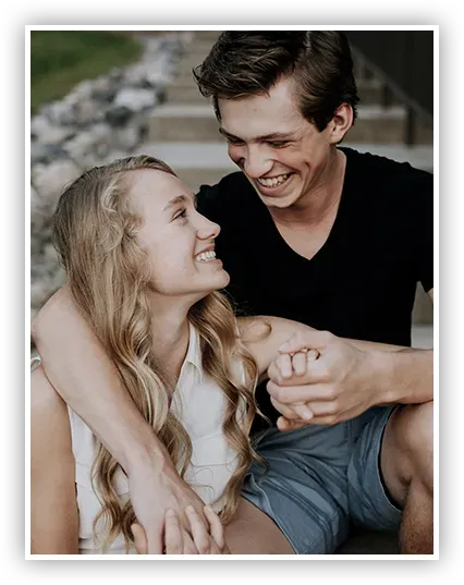 A man and a woman are holding hands and smiling while sitting on a set of stairs.
