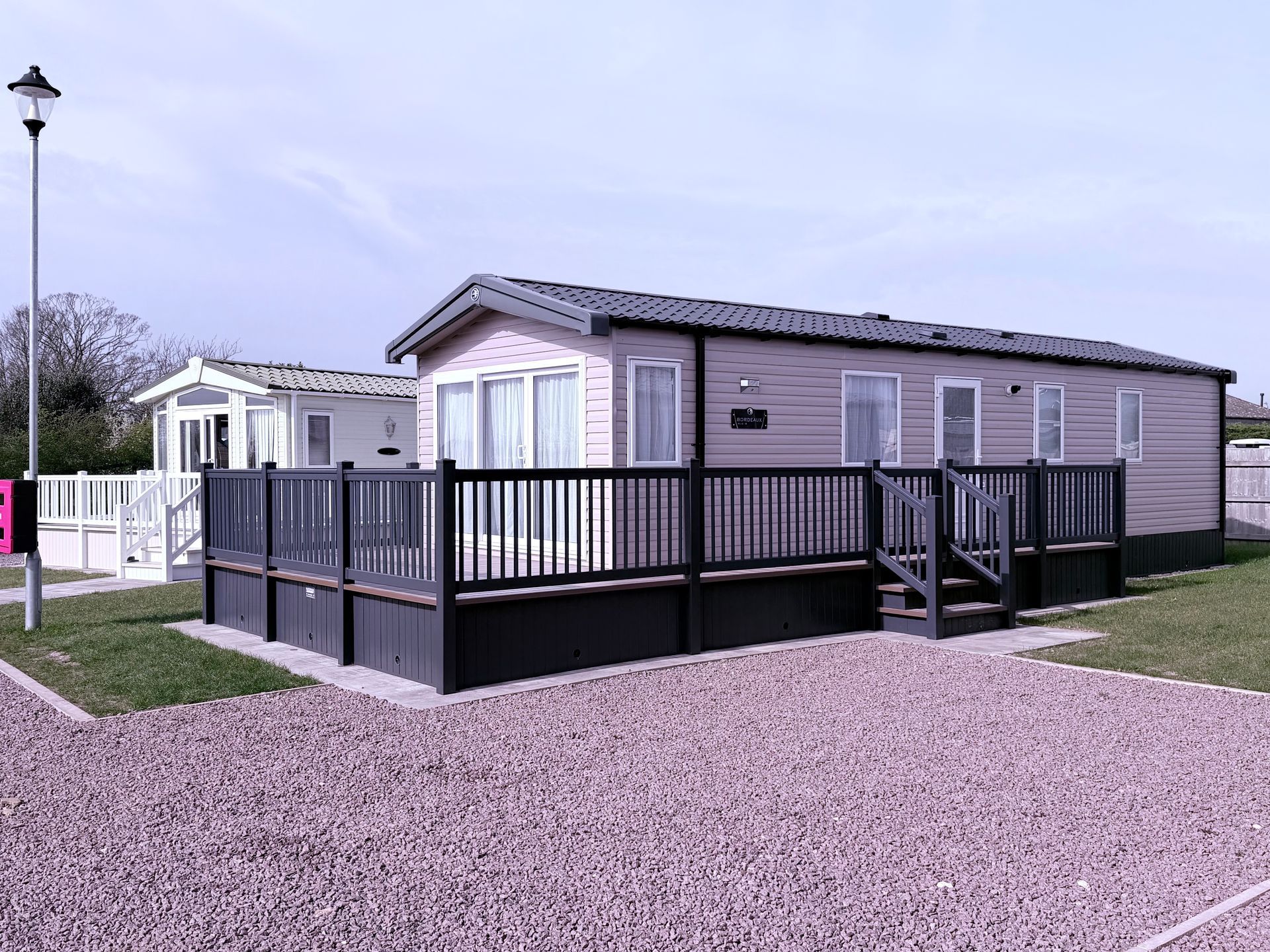 a photograph of two static caravans with deckings on. the one in front has a black deck
