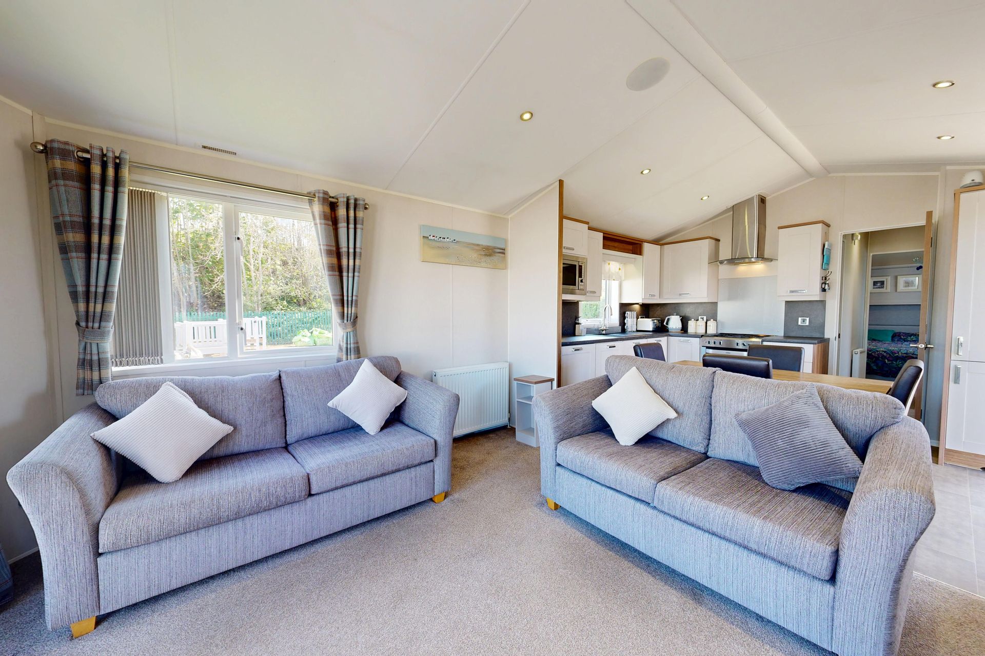 a caravan front room with two grey sofas and window letting light in