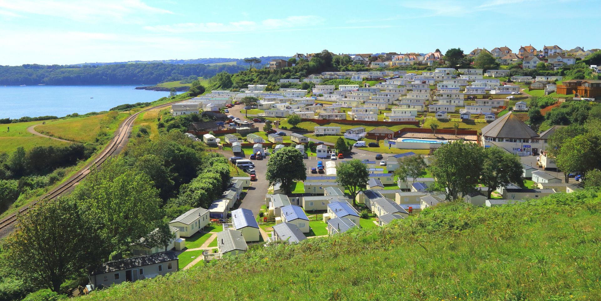 an arial shot of a caravan park overlooking the sea with a railway line in the front
