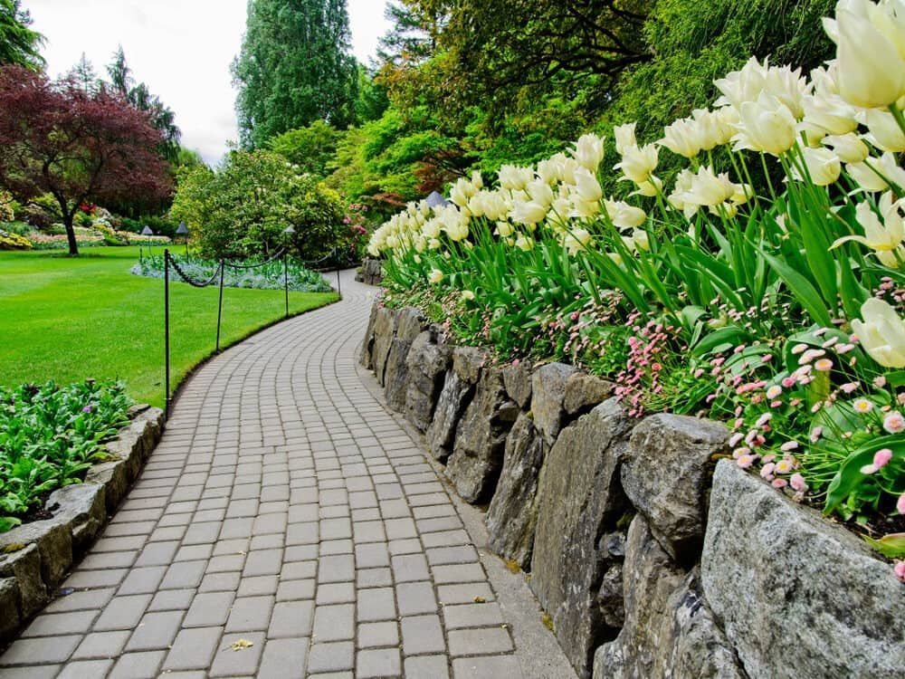 A Brick Walkway In A Park Surrounded By Flowers And Trees — Paxi Homes Brad Clarke in Port Macquarie, NSW