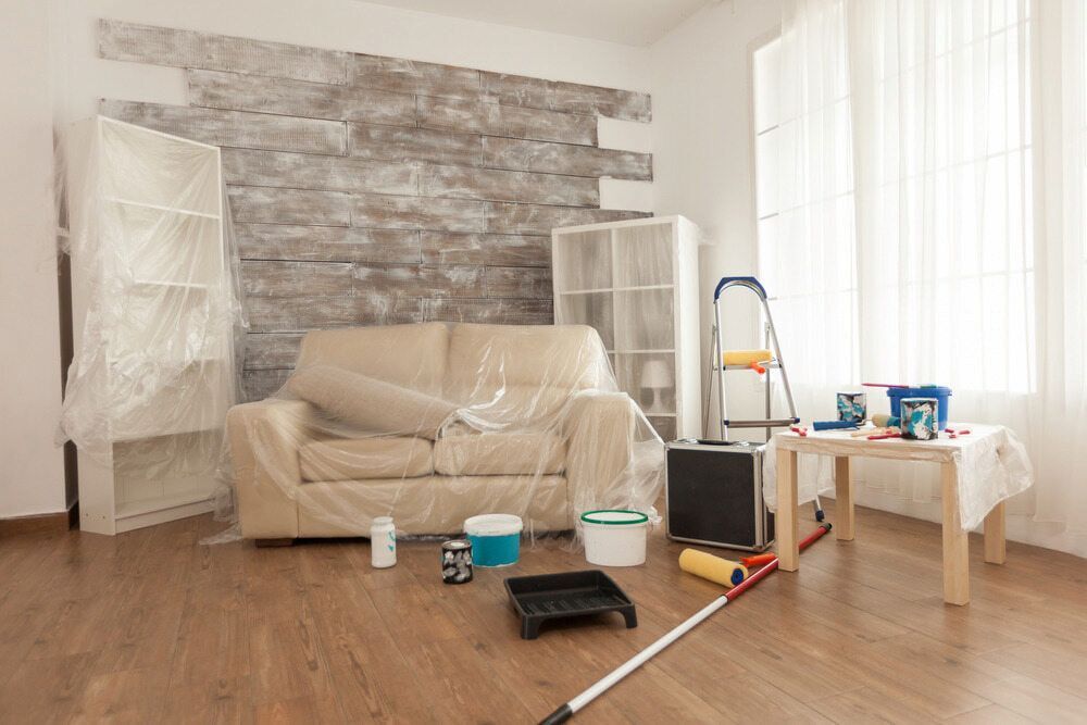 A Living Room Is Being Painted With A Couch Covered In Plastic — Paxi Homes Brad Clarke in Port Macquarie, NSW