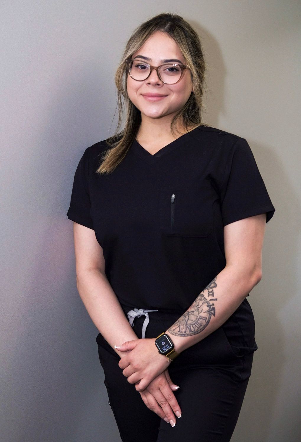 A woman in a black scrub top is smiling for the camera.