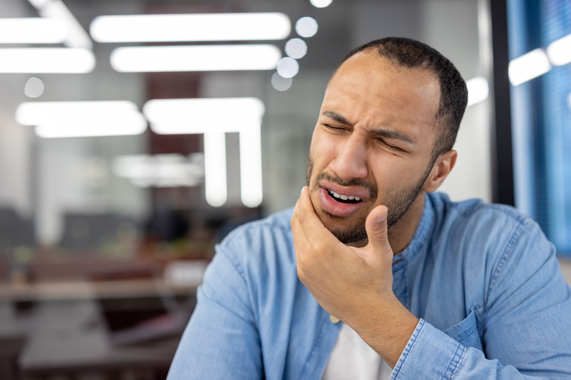 A man is holding his face in pain because he has a toothache.