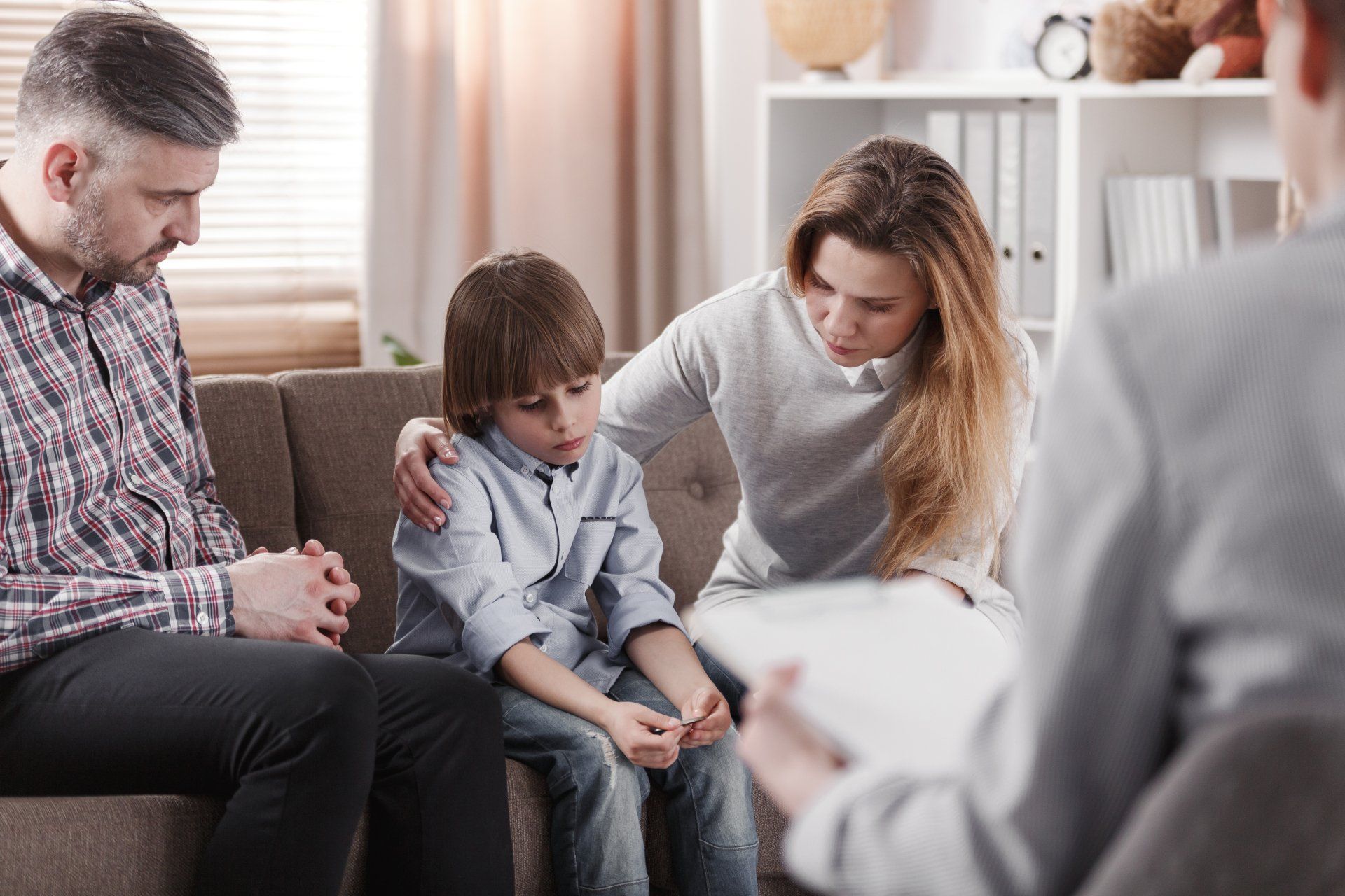 A family is sitting on a couch talking to a counselor.