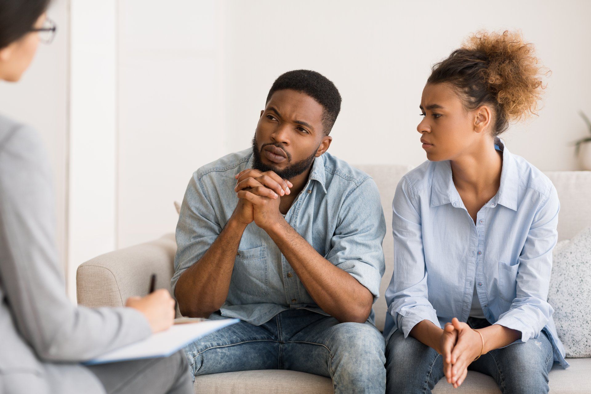 A man and a woman are sitting on a couch talking to a therapist.
