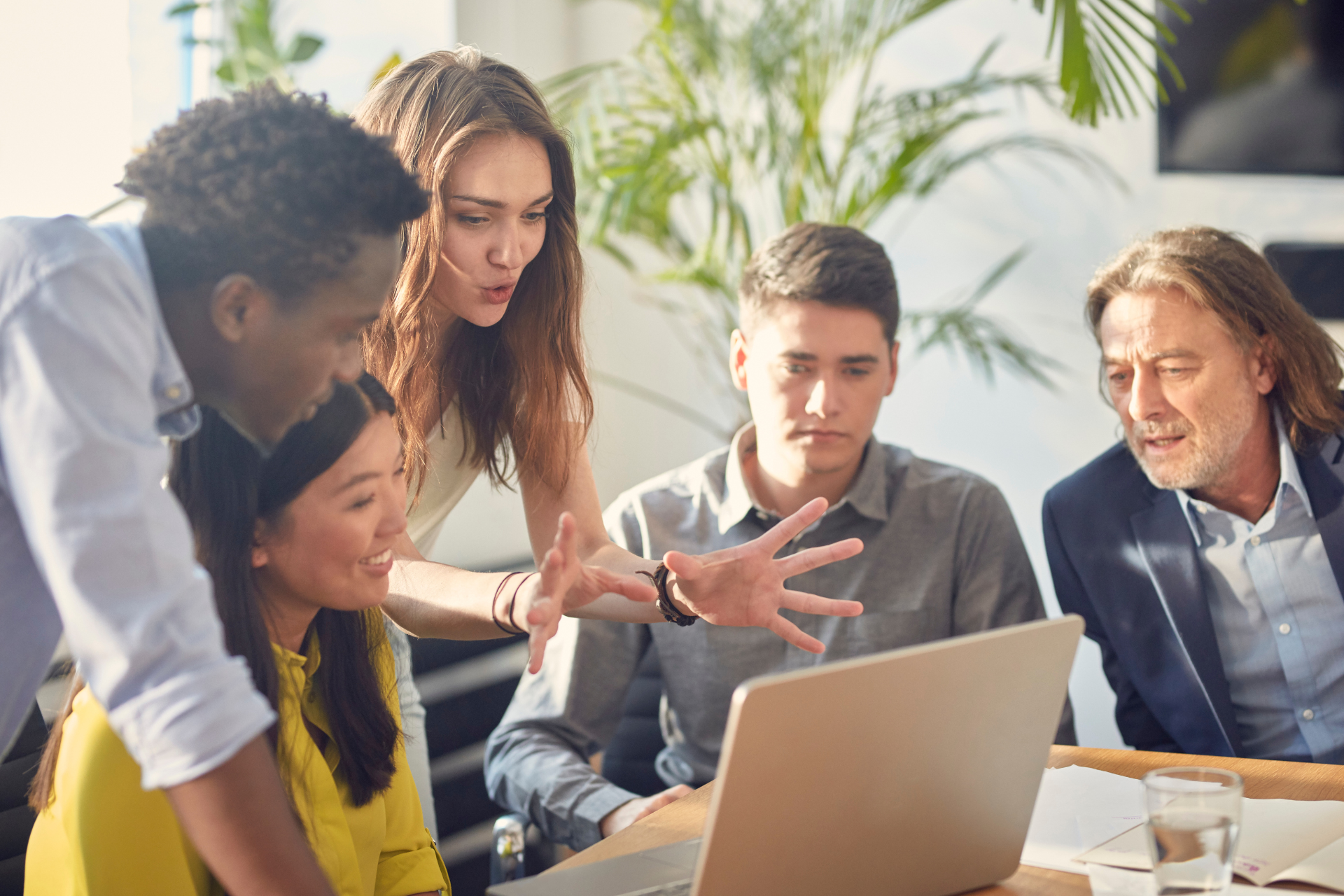 A group of people are sitting at a table in front of a computer.