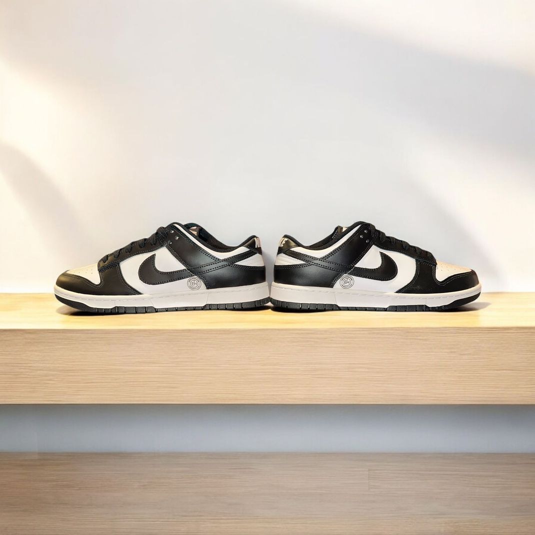 A pair of black and white nike dunk low sneakers are sitting on a wooden shelf.