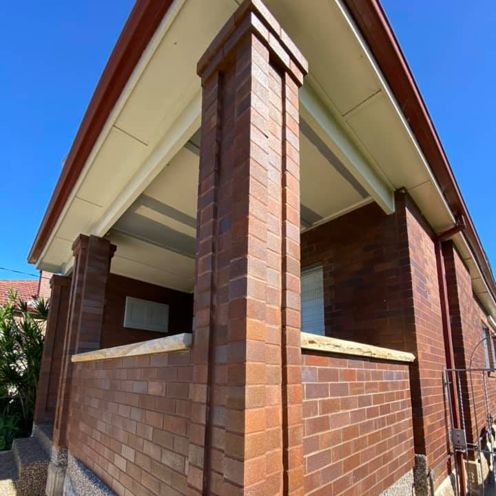 A brick building with a porch and a blue sky in the background