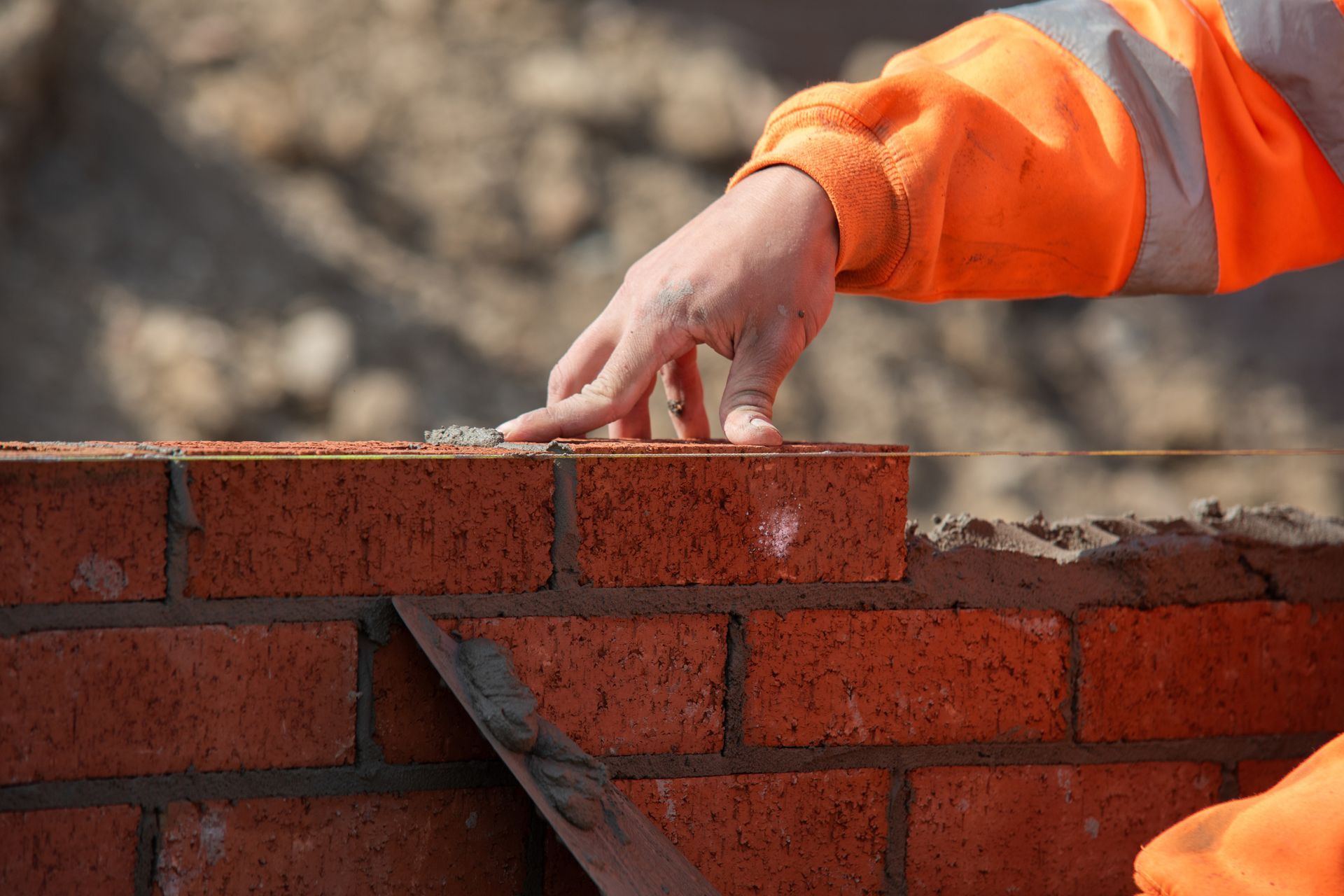 Bricklayer carefully laying red bricks during residential home construction.