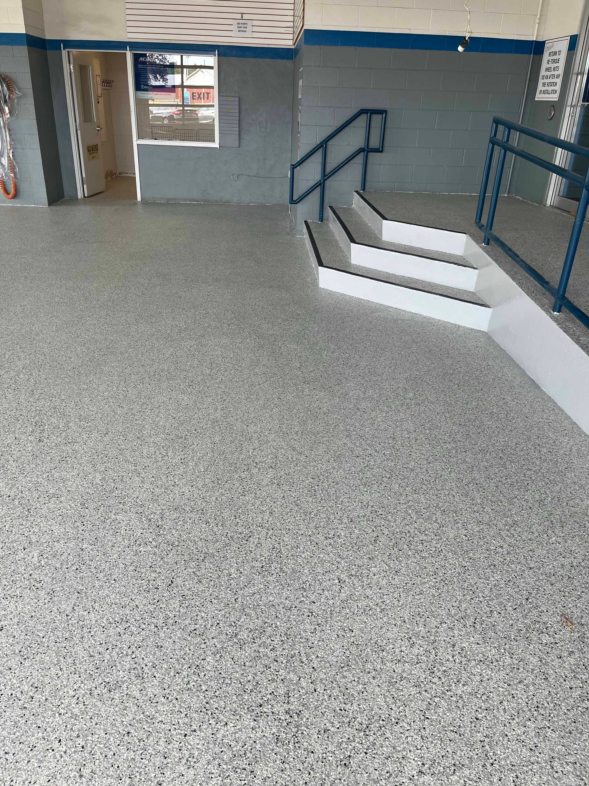 A room with a staircase and a concrete floor.