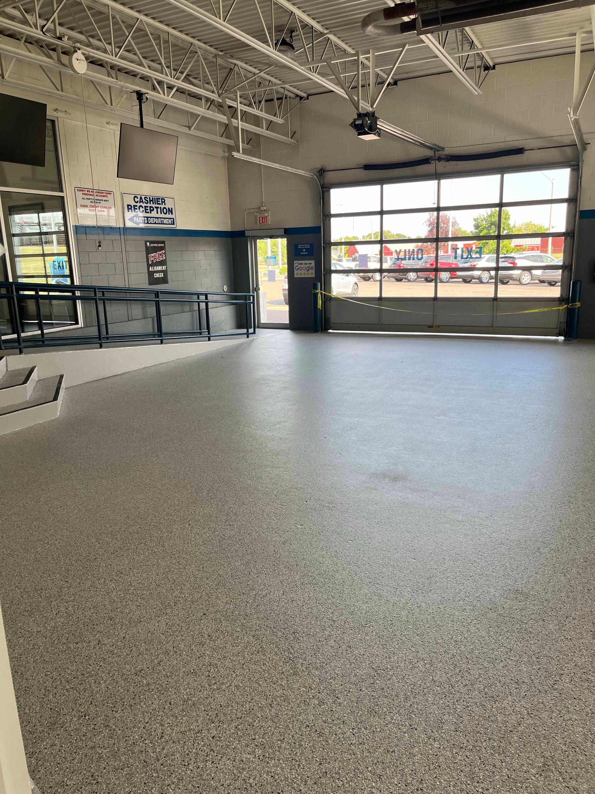 A large empty room with a gray floor and a garage door.