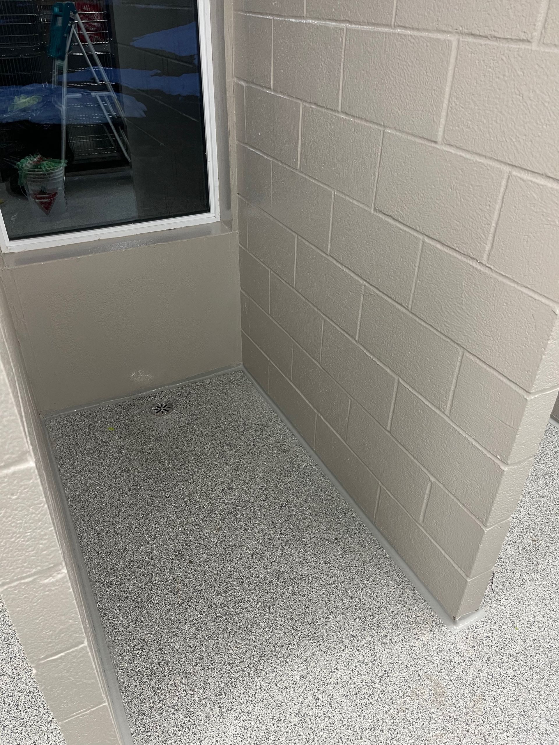 A corner of a room with a brick wall and a window.